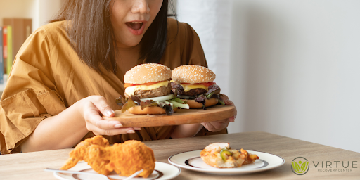 women have burgers n hand